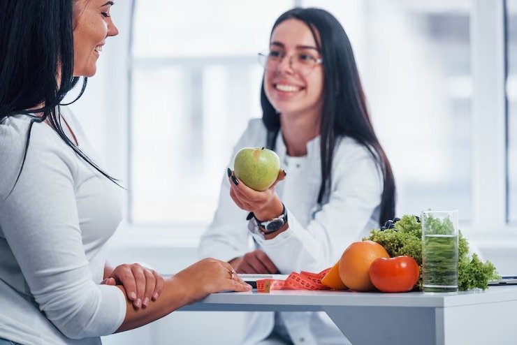 imgi_9_nutricionista-mujer-sosteniendo-manzana-verde-da-consulta-al-paciente-interior-oficina_1
